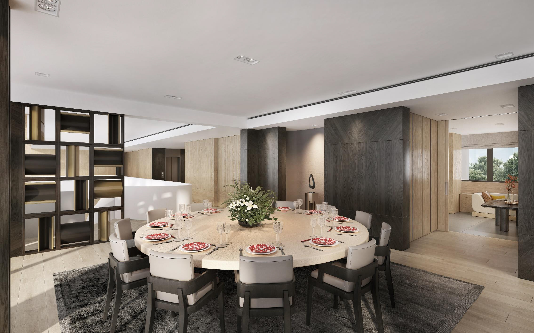 21 Anderson penthouse dining room with a large, round table set for a meal. The room features a neutral color palette with dark wood accents, recessed lighting, and a patterned rug. The table is surrounded by ten upholstered chairs and set with plates and a floral centerpiece.