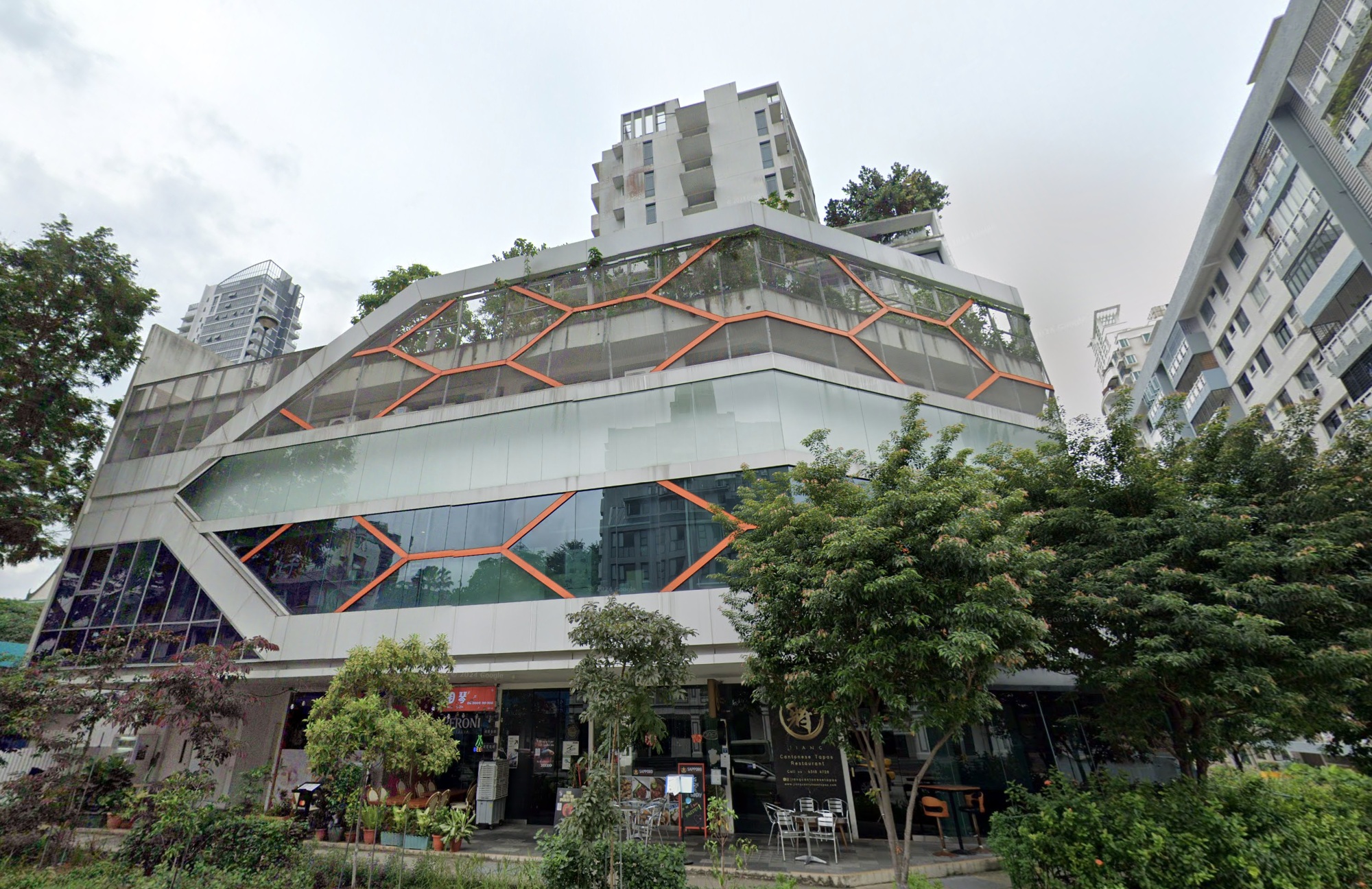 A multi-level commercial building with a unique, modern architectural design, featuring angular lines, large windows, and orange geometric patterns.