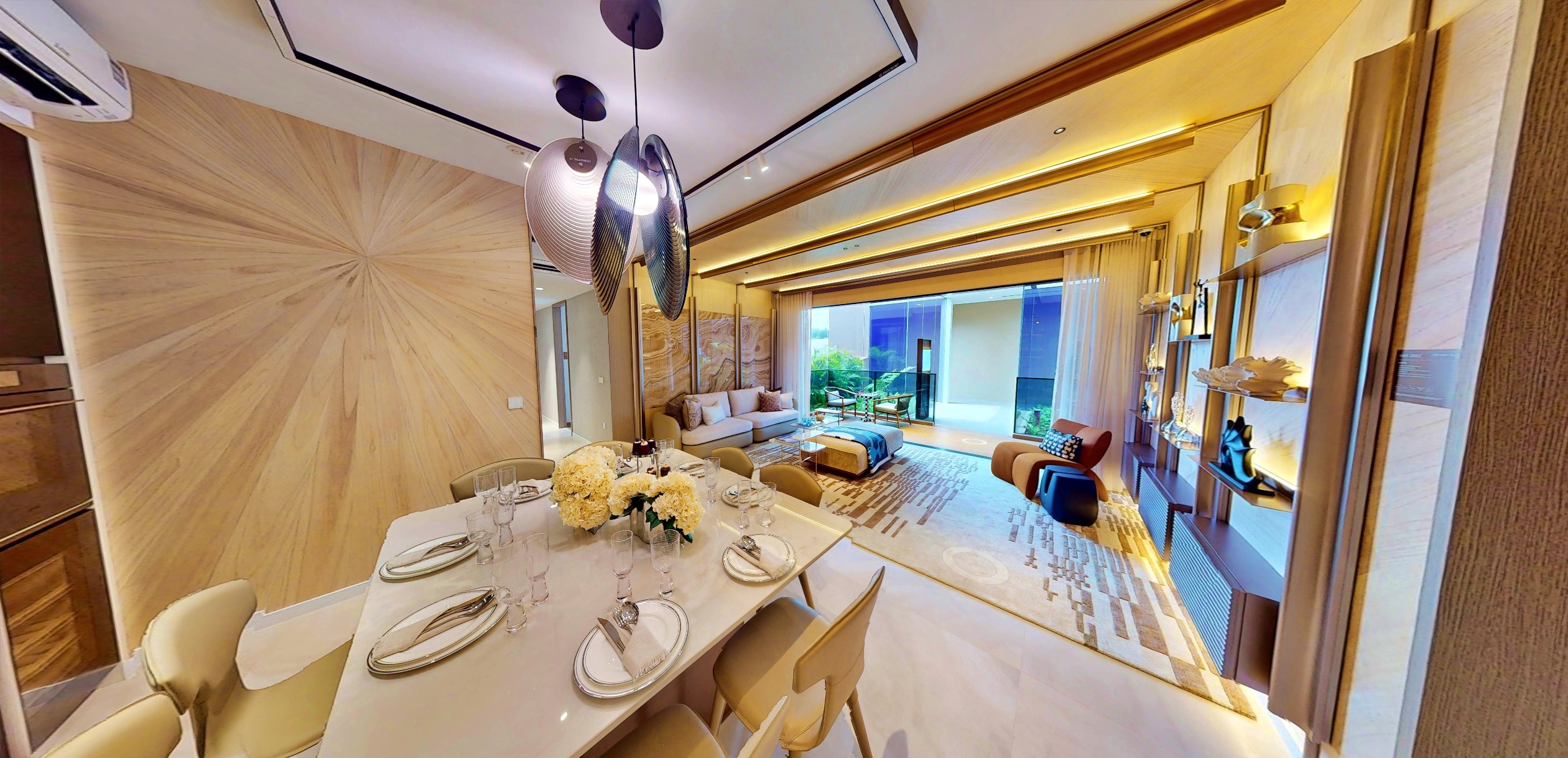 Interior photograph of a modern apartment with a dining table set for six, a living area with sofa and armchairs, and a balcony with sliding doors.