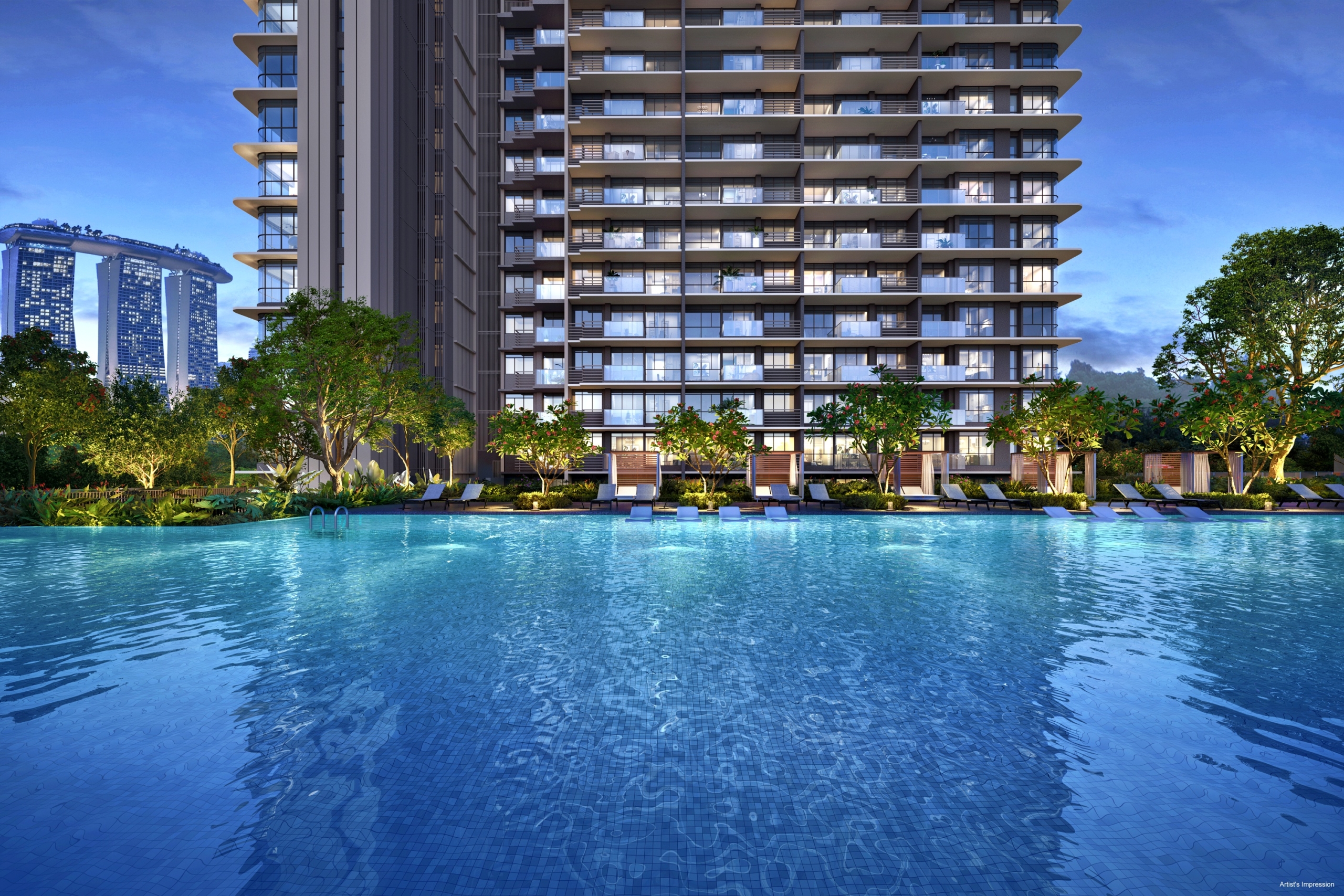 Modern high-rise residential building with a large swimming pool in the foreground. Marina Bay Sands hotel is visible in the distance on the left. The building is illuminated with warm lights, and the pool reflects the ambient light. Trees and lounge chairs surround the pool.