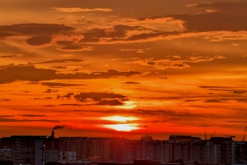 A vibrant orange and red sunset over a city skyline.
