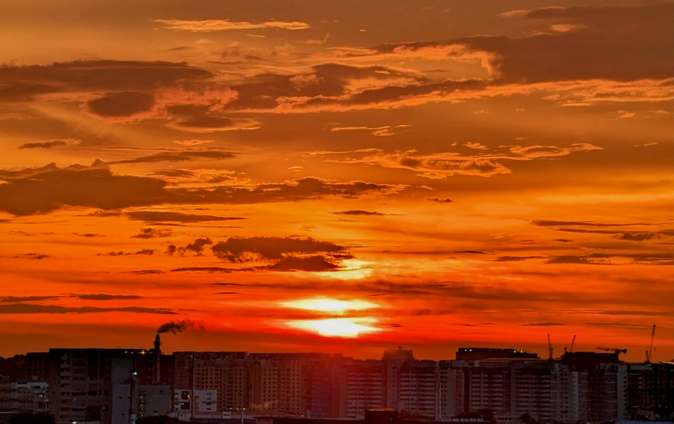 A vibrant orange and red sunset over a city skyline.