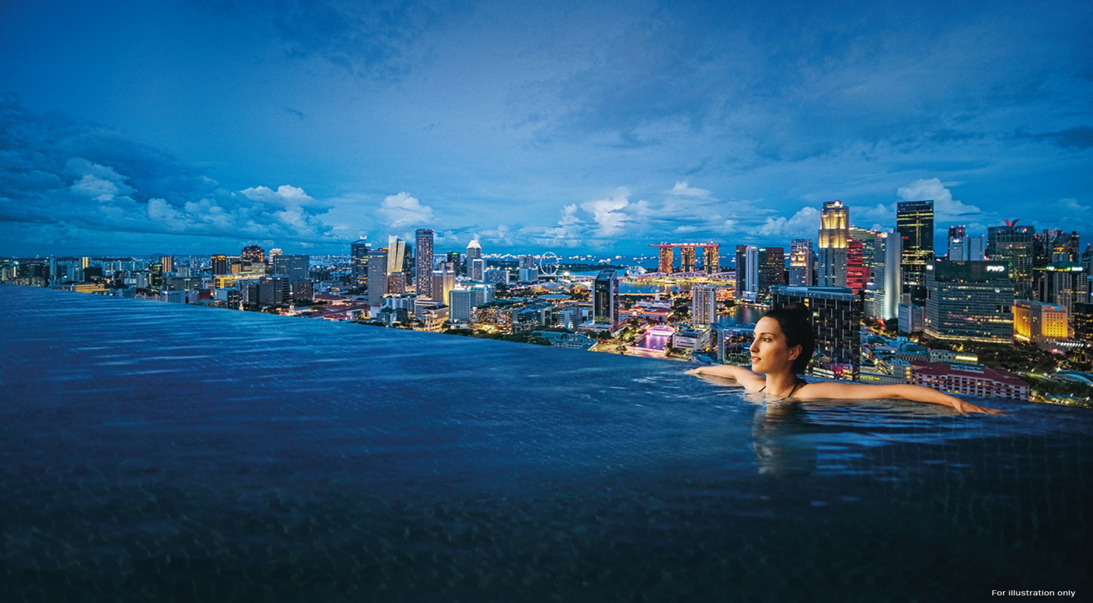 A woman in an infinity pool overlooking the illuminated Singapore skyline at dusk.